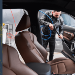 Man cleaning a car floor mat with a brush, ensuring a spotless and well-maintained interior.